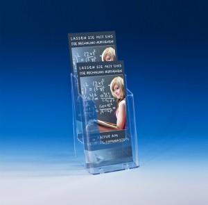 Image-Flyer präsentieren Sie ansprechend und organisiert mit Prospektständern. Vor einem blauen Hintergrund ist ein transparenter Prospektständer mit zwei Etagen platziert. In die Fächer ist jeweils ein Exemplar des gleichen Flyers einsortiert. Es handelt sich um einen Image-Flyer für ein Gymnasium. Auf dem Foto ist eine Schülerin vor einer Kreidetafel zu sehen, die mathematische Gleichungen löst. Der Flyer trägt die Aufschrift: "Lassen Sie die Rechnung aufgehen - Abitur am Beispiel-Gymnasium".